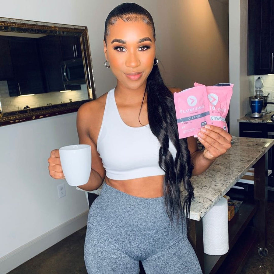 Woman holding 'Flat Tummy Tea' Packets and a cup of tea