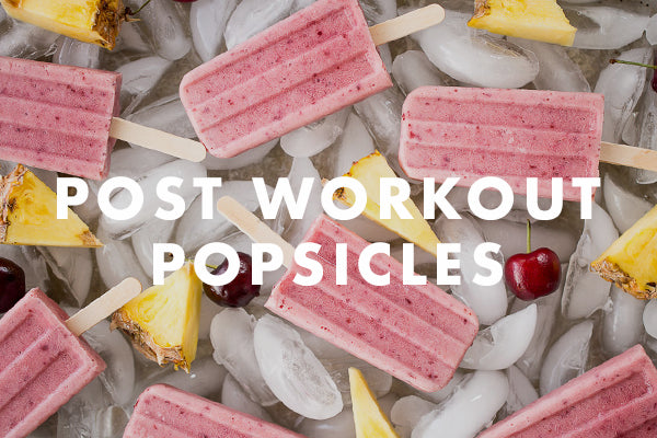 Pink popsicles are scattered over ice with cherries and pineapple pieces. Overlay text reads, "Post Workout Popsicles.