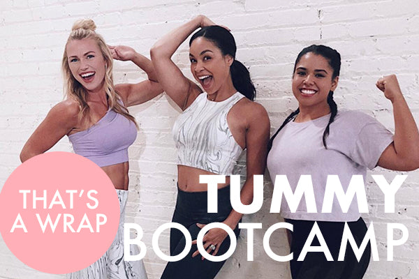 Three women in workout attire pose playfully in front of a white brick wall. Two women are flexing their biceps, while the woman in the center raises an arm overhead. The text reads "That's a Wrap - Tummy Bootcamp.