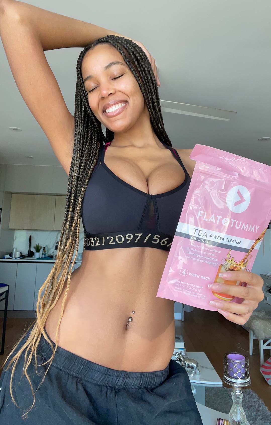 Happy woman holding a packet of Flat Tummy Tea 4 Week Cleanse.