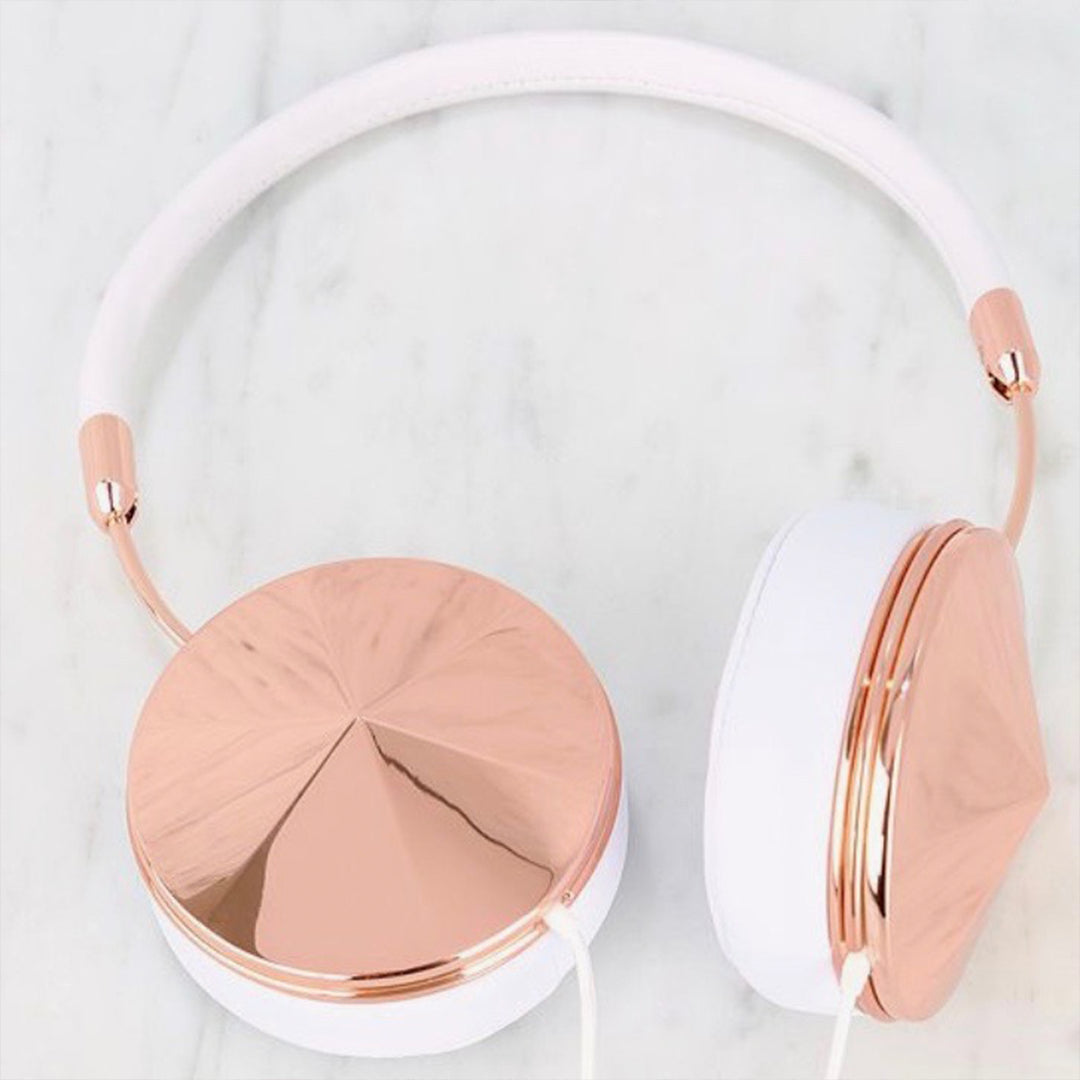 White and rose gold over-ear headphones placed on a marble surface. The ear cups and headband are white with reflective rose gold accents, creating a stylish and modern appearance.