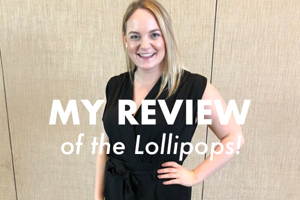 A person in a black outfit stands smiling in front of a beige wall. Bold text on the image reads, "MY REVIEW of the Lollipops!.