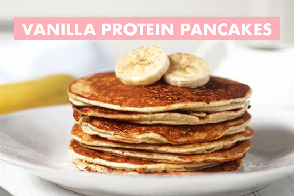 A stack of vanilla protein pancakes topped with banana slices on a white plate. "Vanilla Protein Pancakes" is written in pink on the image.