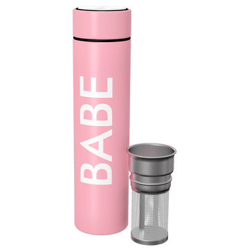 A pink thermos with "BABE" written vertically in large white letters and a black rim around the lid sits next to a Flat Tummy Co metal tea infuser for loose leaf tea, featuring a mesh body and solid top.