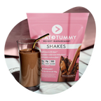 A glass of chocolate shake is placed next to a pink pouch labeled "Flat Tummy Shakes." The packaging has images of flowing chocolate and text about weight management.