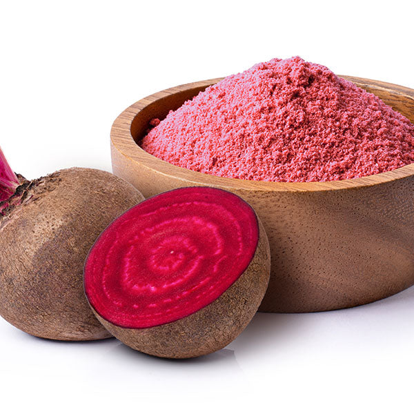 A wooden bowl filled with beet root juice powder is placed next to a whole beetroot and a halved beetroot.